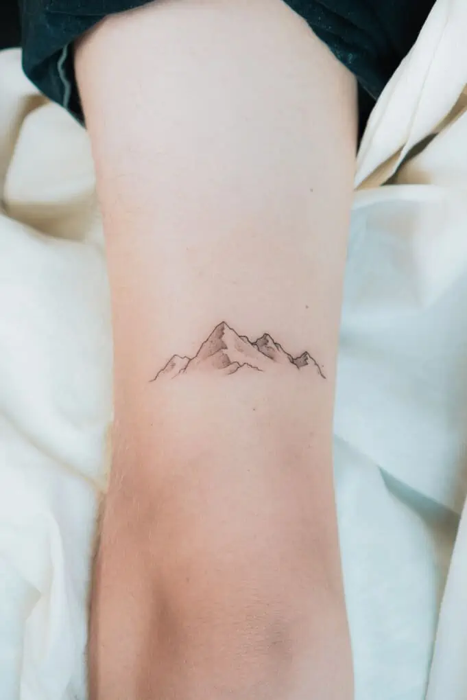 Minimalist mountain tattoo on the rib.