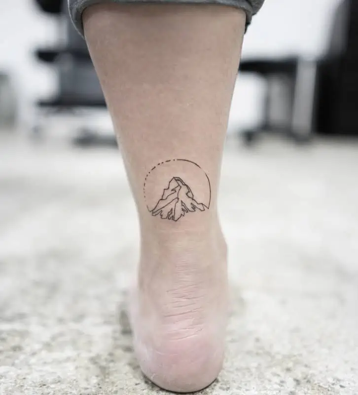 Tatouage géométrique de montagne avec cercle à la cheville